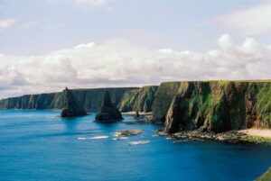 A large body of water surrounded by a lush green hillside